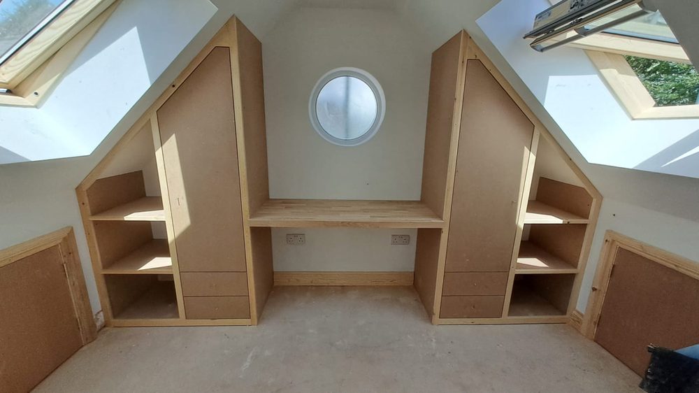 Loft storage built to follow the roofline, with a central desk and velux windows