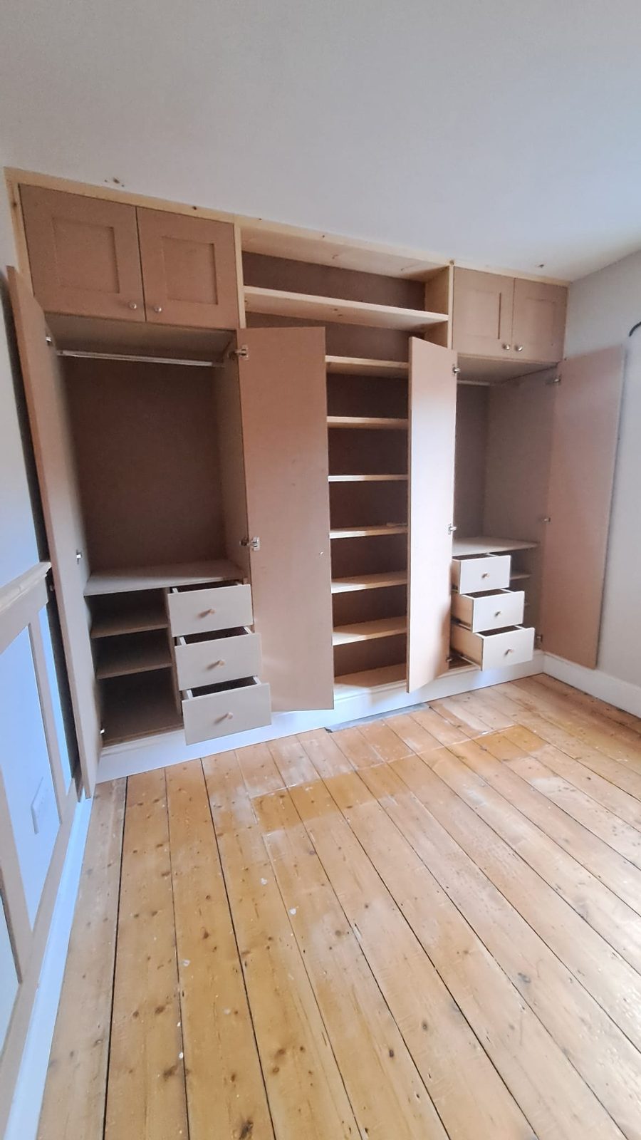 Floor-to-ceiling shaker wardrobes flanking a Victorian fireplace